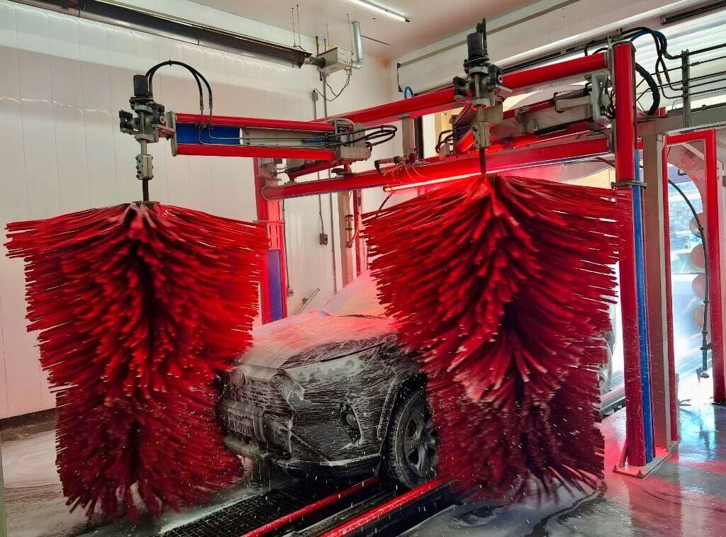 Brightworks Granbury exterior wash — dual red wraparound brushes hugging a dark SUV under red accent lighting