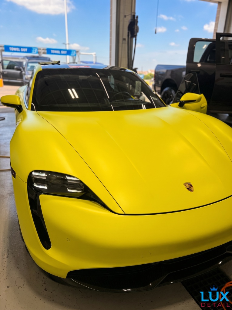 Yellow Porsche Taycan angled front view in the Brightworks detail bay — showroom-quality shine after full detail