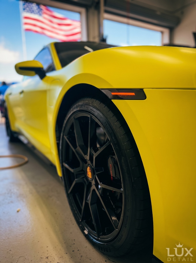 Yellow Porsche 911 GT3 rear quarter panel and wheel arch detail — American flag backdrop at Brightworks